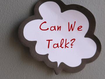 A white speech bubble with red text that says "can we talk?" on a gray background