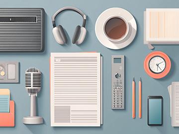 An aerial view of a blue desk with keyboard, headphones, coffee, notes, microphone, and more on the table.