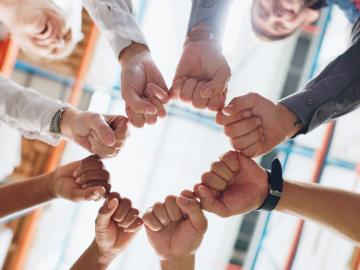 A group of people reaching their hands into a circle to celebrate