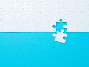 A white puzzle with a missing puzzle piece on a blue background
