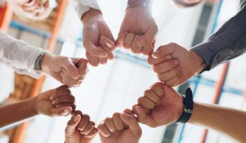 A group of people reaching their hands into a circle to celebrate